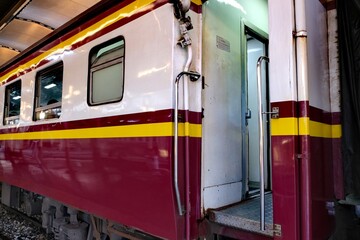 Exterior view of a maroon, white, and yellow train car with an open door and windows
