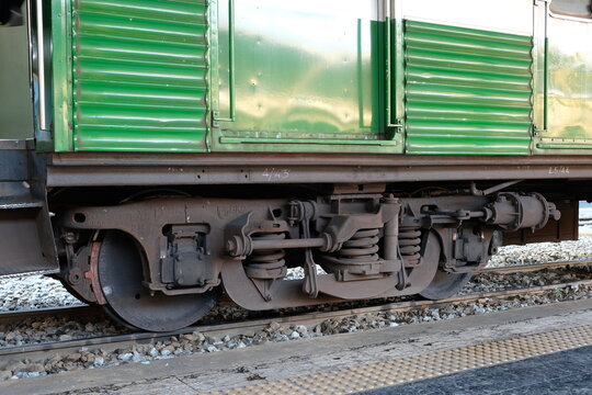 Close-up view of a green train's undercarriage and wheel assembly on tracks