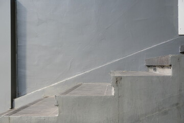 Minimalist concrete staircase with a textured gray wall and subtle shadow play