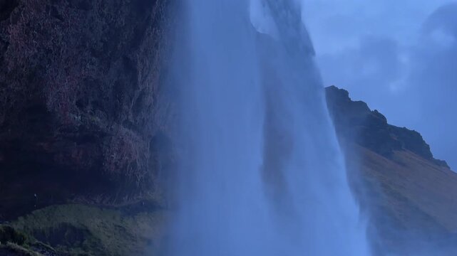 Tilt Shot Behind Seljalandsfoss Waterfall on a Cloudy Winter Day, Iceland.