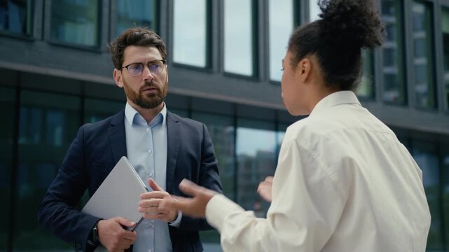 Aggressive African businesswoman boss leader angry firing Caucasian businessman male worker two multiethnic business people female scolding conflict leadership corporate stress outdoors city workplace