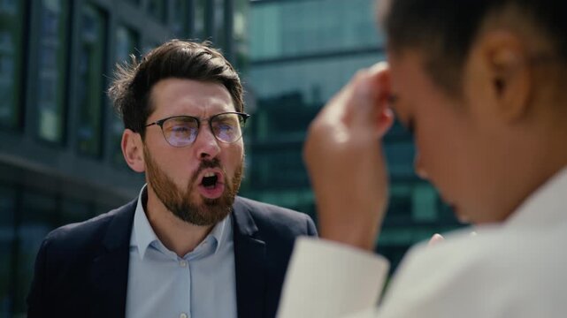 Furious angry Caucasian businessman male boss yelling scolding African American businesswoman female aggressive frustrated workplace conflict problem office bullying corporate stress outside street