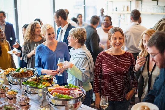 A diverse group of people enjoying a buffet at a social event. Smiling guests, diverse crowd, buffet food, and socializing in a lively atmosphere. Diverse people mingle at a social event.