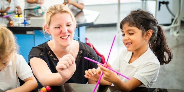 A teacher and young student in a classroom, in science activity. The teacher guides the student, fostering learning and curiosity in a fun environment. Teacher working with elementary school children.