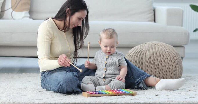 Mother and her baby boy playing with toy xylophone at home