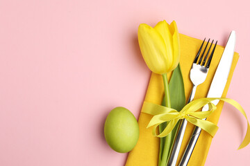 Easter celebration. Festive table setting with floral decor and painted egg on pink background,...