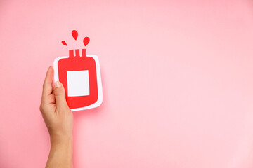 Hand holds a red bottle shape symbolizing blood donation