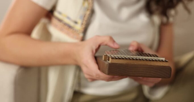Woman playing kalimba at home, closeup. Musical instrument