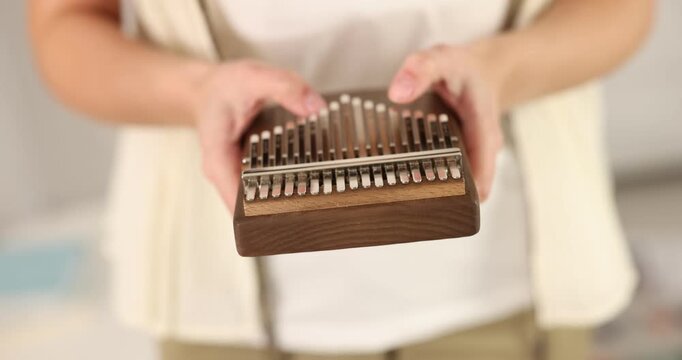 Woman playing kalimba at home, closeup. Musical instrument
