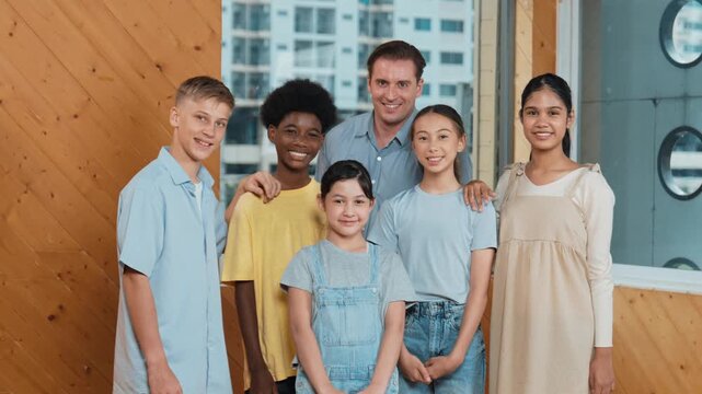 Happy teacher and diverse student standing while smilling to camera. Professional smart instructor with high school children with mixed races in casual outfit pose at camera with cheerful. Edification
