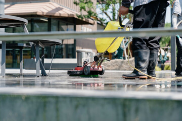 The janitor is cleaning the floor with a floor scrubber.