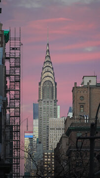  New York, NY- Dec. 20, 2025: Manhattan neighborhood buildings with Chrysler Building skyline at dusk with pink sunset sky. Vertical orientation. 