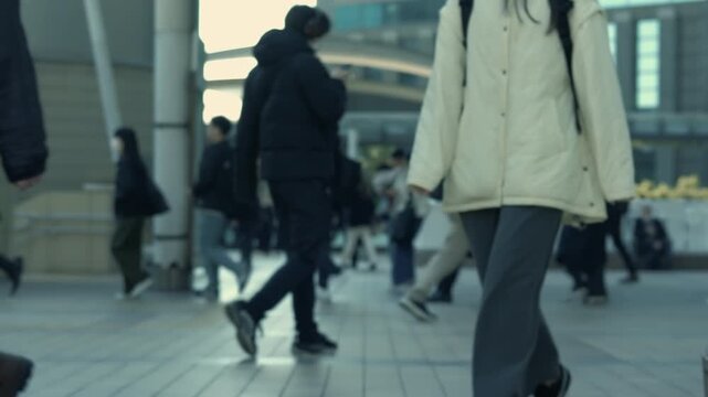 Mid-section view of commuters walking in winter jackets on a busy Tokyo street.