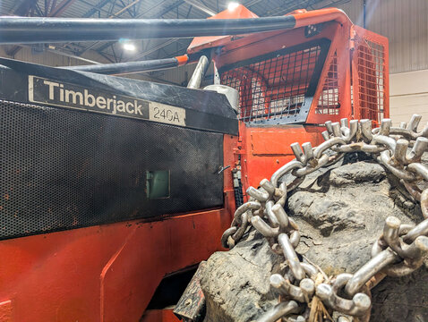 Canada, Quebec, 05 December 2025 : Red timberjack forestry machine inside warehouse with chained mud covered tire