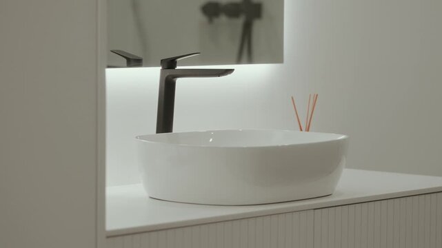 Minimal bathroom interior with white vessel sink and black faucet