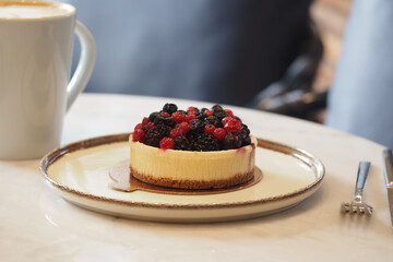 Cheesecake with berries on a plate beside a cup of coffee © Towfiqu Barbhuiya 