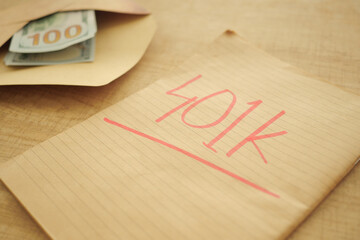 Money in an envelope labeled 401k on a wooden table