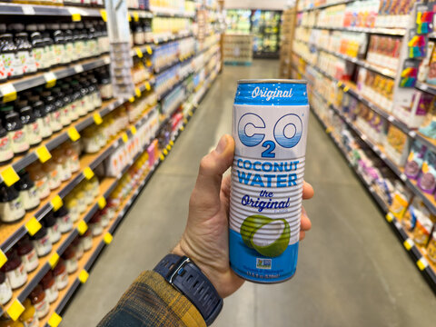 C2O Coconut Water Can Held In Grocery Store Aisle