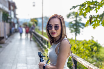 Portrait of a female traveler with a camera walking by the river in a peaceful town.