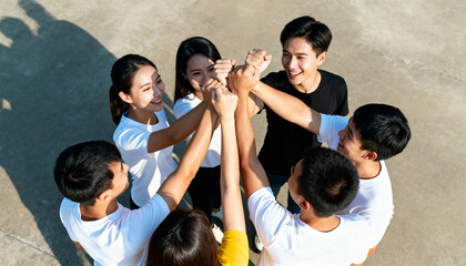 Group of asian people forming circle and joining hands in teamwork and friendship