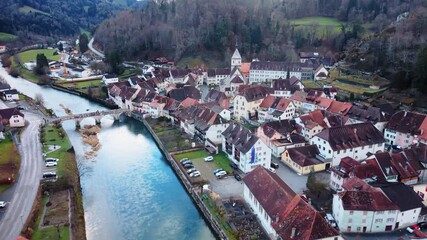 Aerial: Saint-Ursanne cityscape during the day in Clos du Doubs, canton of Jura, Switzerland, pull out drone shot