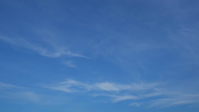 A calm blue sky timelapse video with thin, wispy clouds gently flowing across a vast clear atmosphere, emphasizing smooth cloud motion, openness, and the peaceful beauty of a serene daytime sky.
