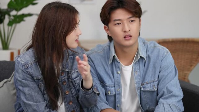 Young Asian Couple in Denim Jackets Reacting with Disgust and Worry