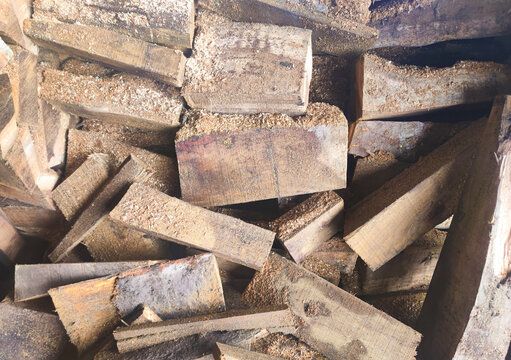 Close-up of rough cut wooden blocks stacked tightly, covered with sawdust and raw textures, representing forestry materials, woodworking processes, and natural construction resources
