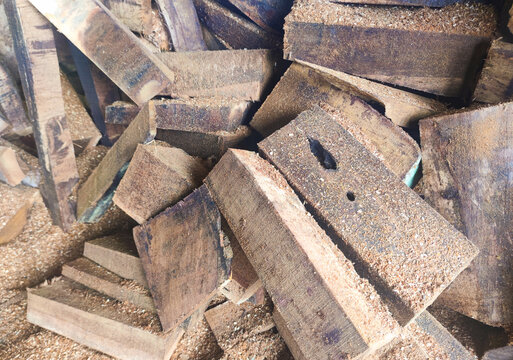 Close-up of rough cut wooden blocks stacked tightly, covered with sawdust and raw textures, representing forestry materials, woodworking processes, and natural construction resources
