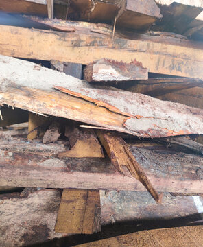 Close-up of stacked rough wooden planks showing raw natural texture, saw marks, bark edges, and rugged lumber surface used for carpentry, woodworking, and construction material supply