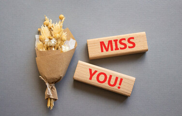 Miss you symbol. Concept word Miss you on wooden blocks. Beautiful grey background with bouquet of flowers. Business and Miss you concept. Copy space