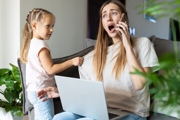 Stressed woman working from home while talking on phone and caring for daughter