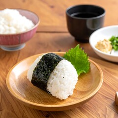 Rice ball wrapped in seaweed on wooden plate with other dishes, placed on wooden table surface
