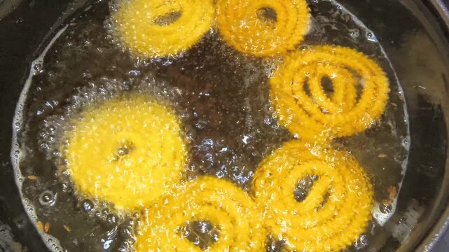 Making of chakli footage captures the traditional frying process of this crispy Indian snack in hot oil. The scene highlights authentic food preparation, texture development, and golden frying stages.
