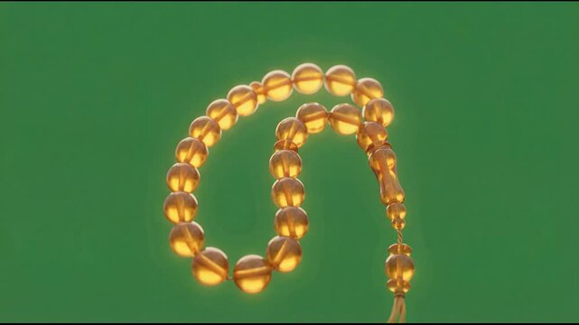 Close-up of Islamic Prayer Beads (Tasbih) with Golden Amber Beads Gently Swaying on a Green Background