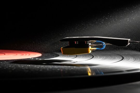 Tonarm einer Vinylplatte setzt auf eine rotierende Schallplatte auf