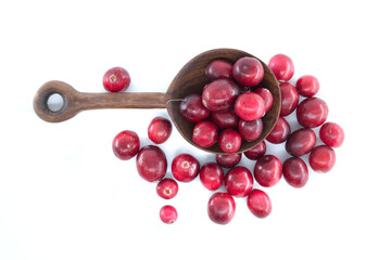 Fresh cranberries in a wooden spoon on a white background, overhead view