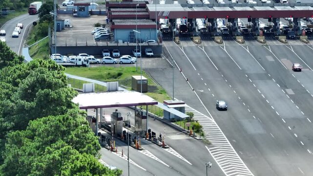 Aerial tilt up reveal from toll booth infrastructure to heavy traffic congestion queues in Rio Grande do Sul, Brazil. 4K 60fps Mavic 3 telephoto footage.