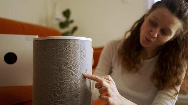 Caucasian woman frowning as she wipes heavy dust from a hepa air purifier filter, illustrating dirty filter, indoor air pollution, maintenance and allergy concern in a home setting