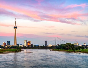 Skyline view of a city with a tall tower and river running in front, under a colorful sunset sky