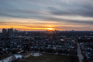 Naklejka premium Toronto city landscape with residential homes and apartment buildings glowing under a vibrant sunset sky, highlighting the urban environment and tranquil evening light