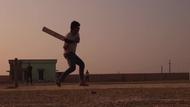 Silhouette of unrecognized Cricket Player Playing at Sunset