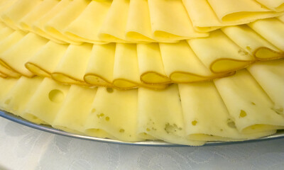 Close up of sliced yellow cheese arranged in layers on a serving platter. Catering food detail suitable for buffet, restaurant service or food background.