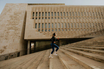 Naklejka premium Woman exercises on steps of building in Malta while doing cardio workout