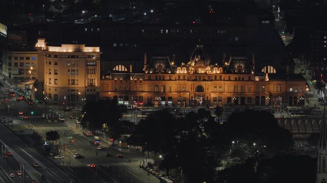 Night aerial of Estacion Constitucion in Buenos Aires, illuminated historic architecture with a cinematic zoom out revealing surrounding streets.