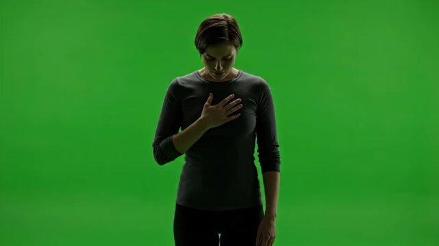 Solemn woman placing hand on chest showing allegiance pledge or heart pain on chroma key green background.
