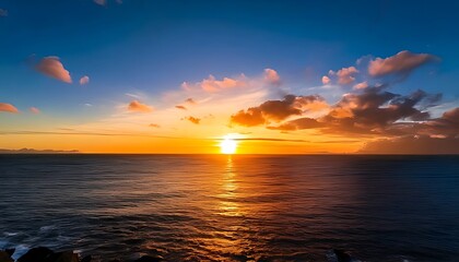 Sunset over a calm sea, sun shining bright, casting golden glow. A few clouds in the sky, varied blues