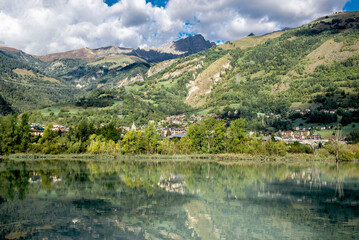 Fototapeta premium view on alpine landscape with green hillsand lake in french alps and town of Bourg Saint Maurice far away