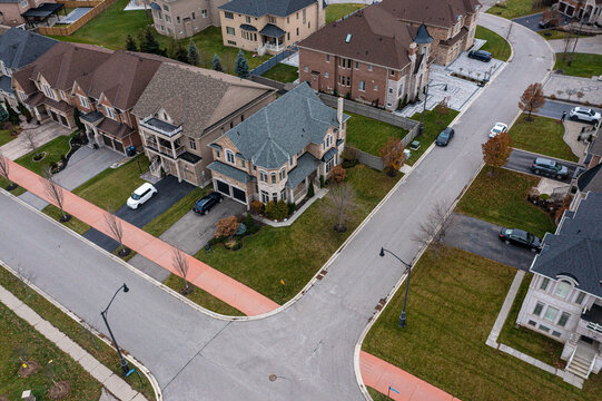Modern suburban neighborhood with a street and large luxury homes featuring well maintained front yards and private driveways, highlighting residential development and community planning
