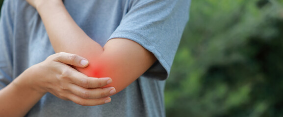 Close-up of woman hand holding painful injured elbow with red inflamed spot. Concept of joint bone...